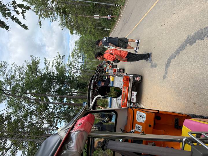 Colorful line of tuk-tuks parked along a rural road while travelers stand nearby