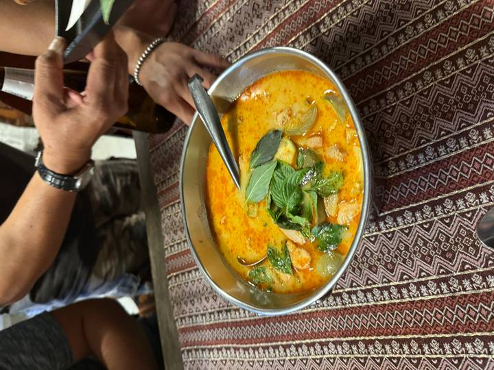 Bowl of spicy creamy soup garnished with basil leaves on a patterned tablecloth