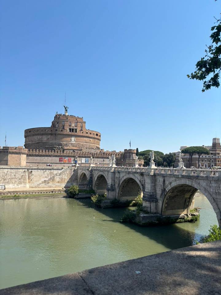Castel Sant’Angelo and the historic bridge spanning the Tiber River under a bright blue Roman sky