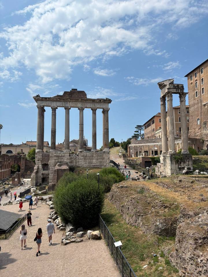 Ruins of the Roman Forum with towering columns and ancient arches against a blue sky