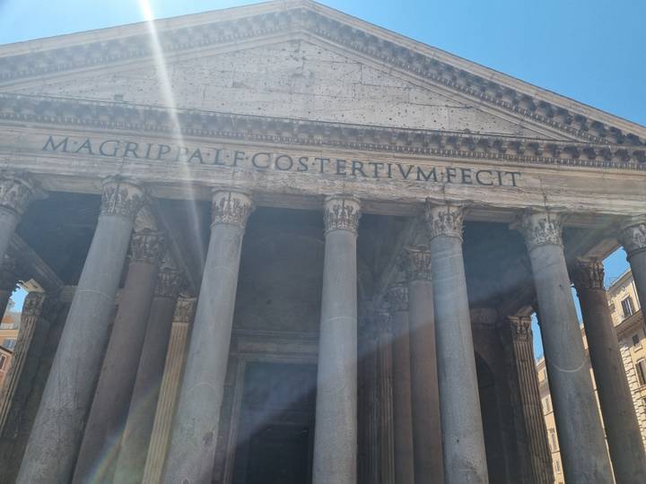 Front portico of the Pantheon with sun flare streaking across ancient columns.