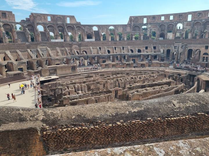 Interior arena view of the Colosseum revealing excavated corridors crowded with tourists.