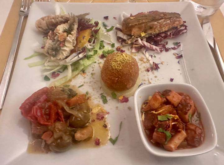 Close-up of an assorted Sicilian antipasto plate with colorful vegetables, croquette and seafood.