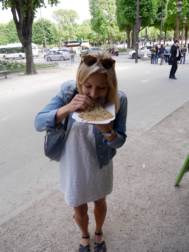 Femme mangeant une crêpe en la tenant dans ses mains.