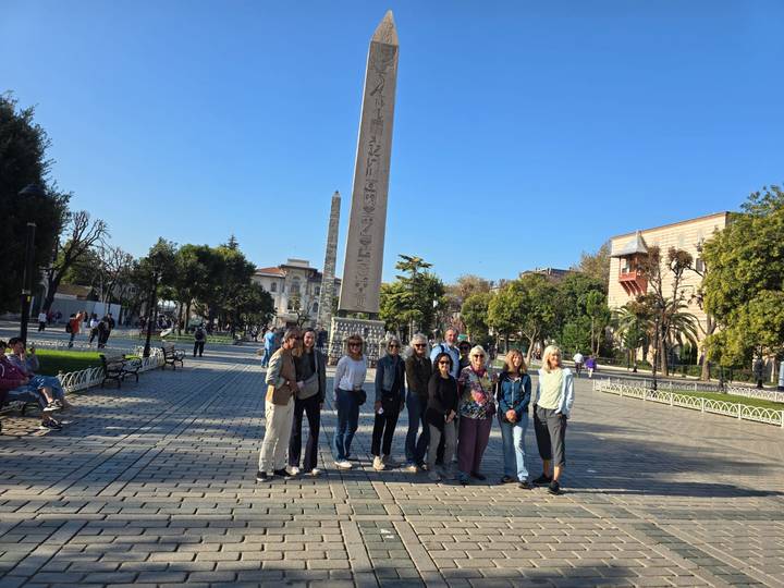 Tour group poses in front of the ancient Egyptian Obelisk at Istanbul’s Hippodrome on a clear day.
