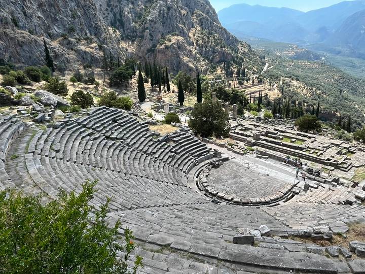 Ancient stone theatre of Delphi overlooking a lush valley and distant hills