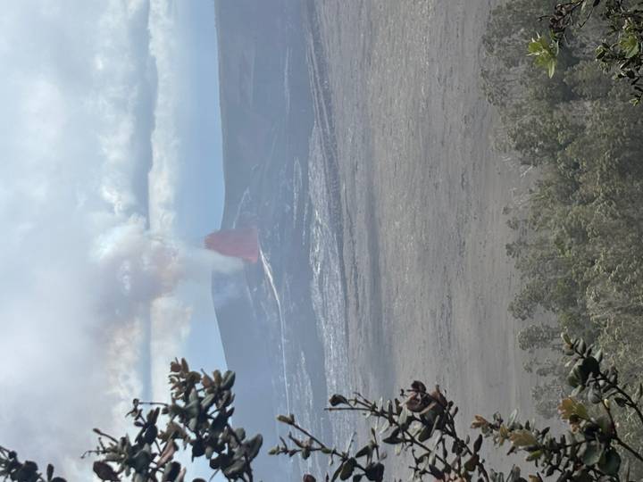 Active volcano erupting with red lava fountain and plume of smoke viewed from distance