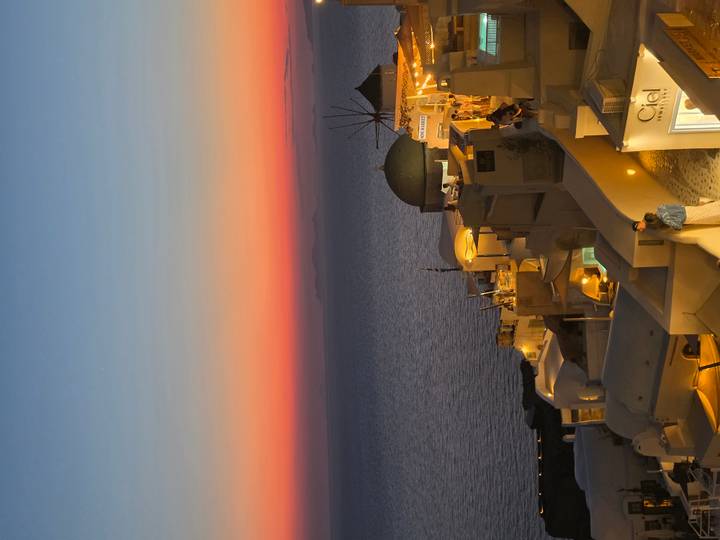 Golden hour view over Oia rooftops and domes with vivid orange-pink sky above the sea.