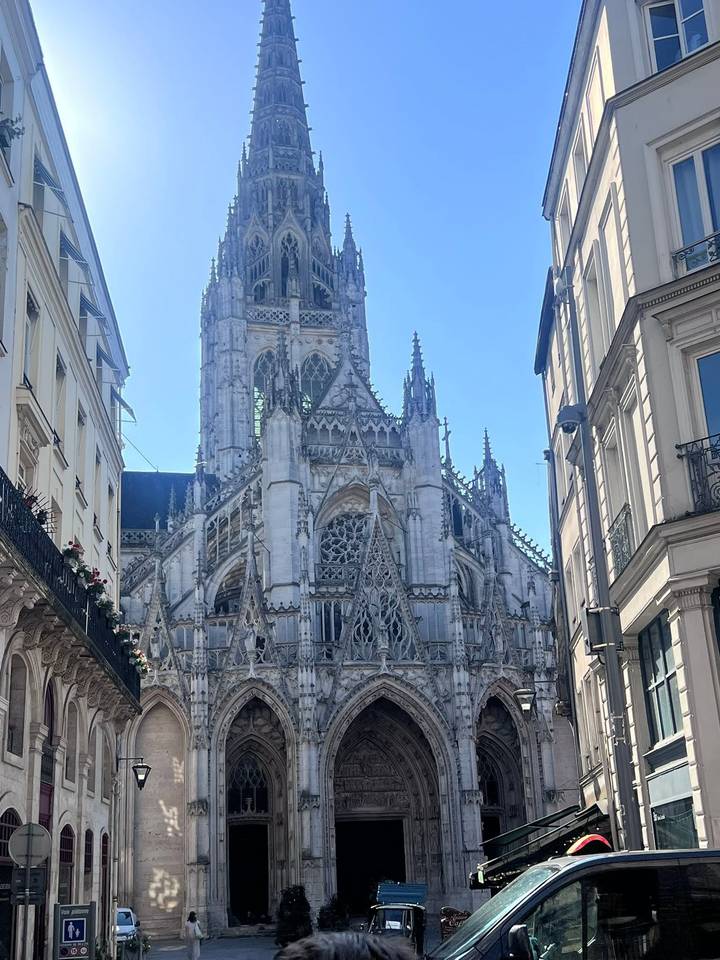 Imposing Gothic Rouen Cathedral rising between narrow city streets under clear sky
