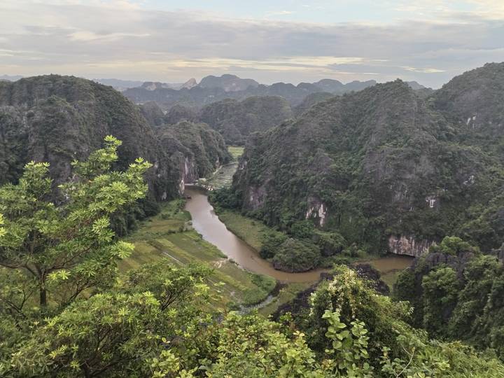 A winding river cuts through lush karst mountains under a pastel evening sky.