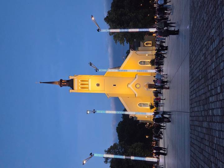 Tallinn's yellow St. John's Church is illuminated at dusk as crowds gather in the square.