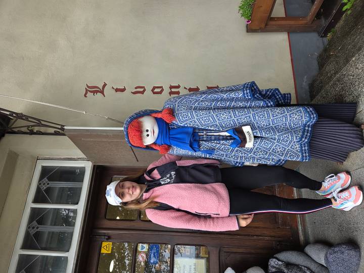 Traveler poses beside a mannequin dressed in blue knitwear outside a boutique doorway.