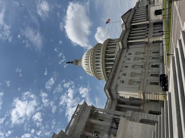 The domed United States Capitol building framed by blue sky and scattered clouds.