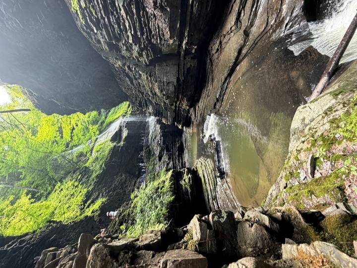 Lush gorge with a small waterfall cascading into emerald pools surrounded by layered rock walls.