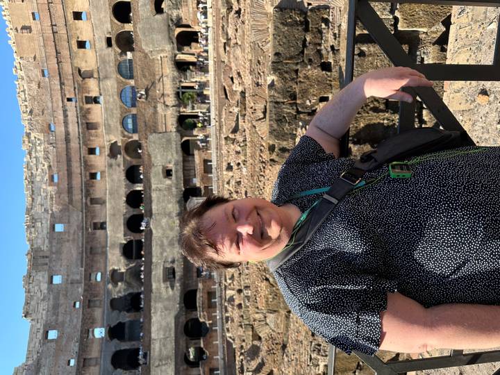 Woman inside the Colosseum interior smiling beside ancient stone tiers.