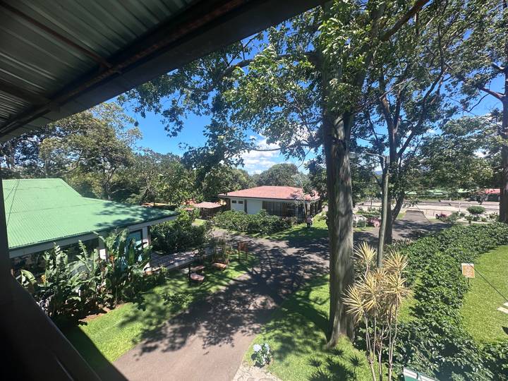 Resort grounds seen from an elevated balcony with gardens and cottages under blue sky.