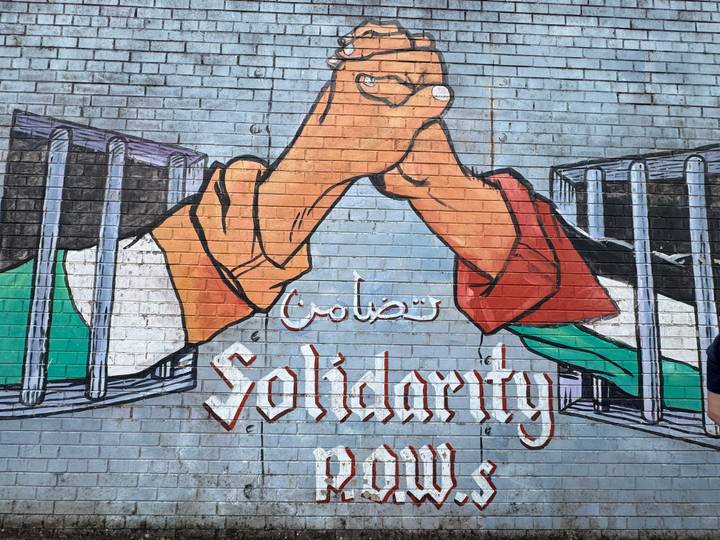 Colorful political mural painted on a brick wall with clasped hands and the word 'Solidarity'.