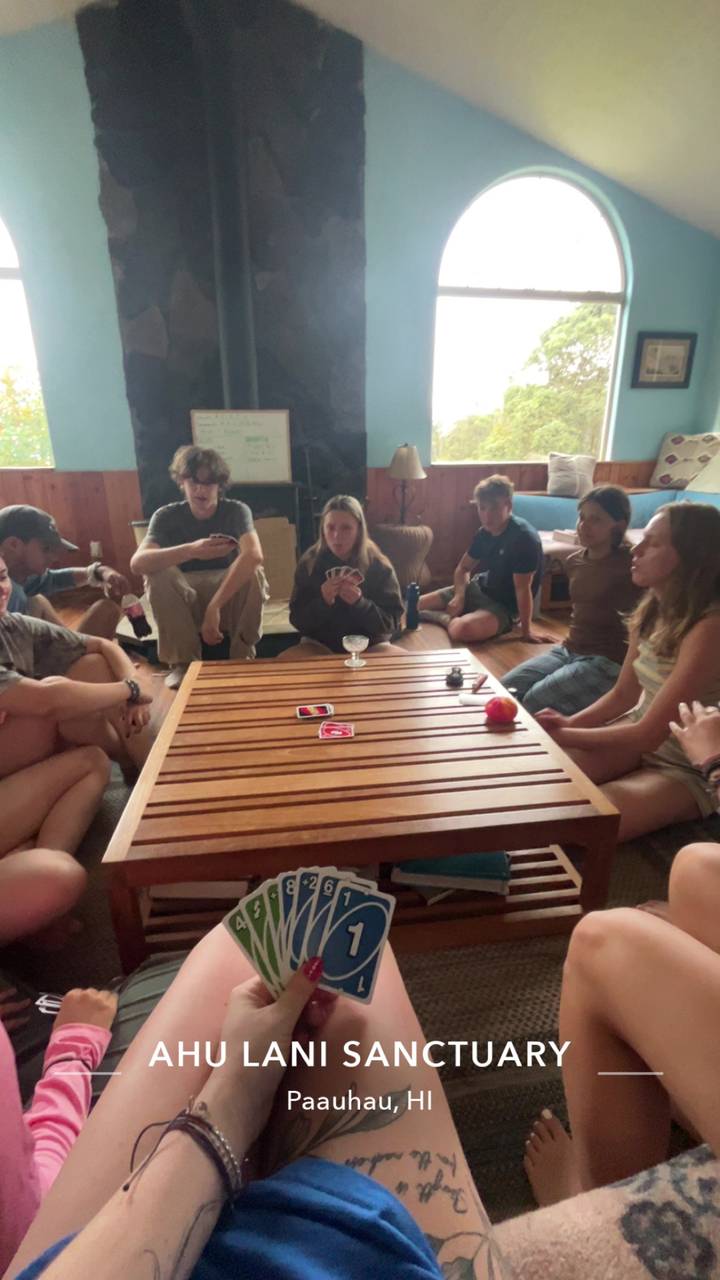 Young travelers gathered around a low table playing cards indoors.