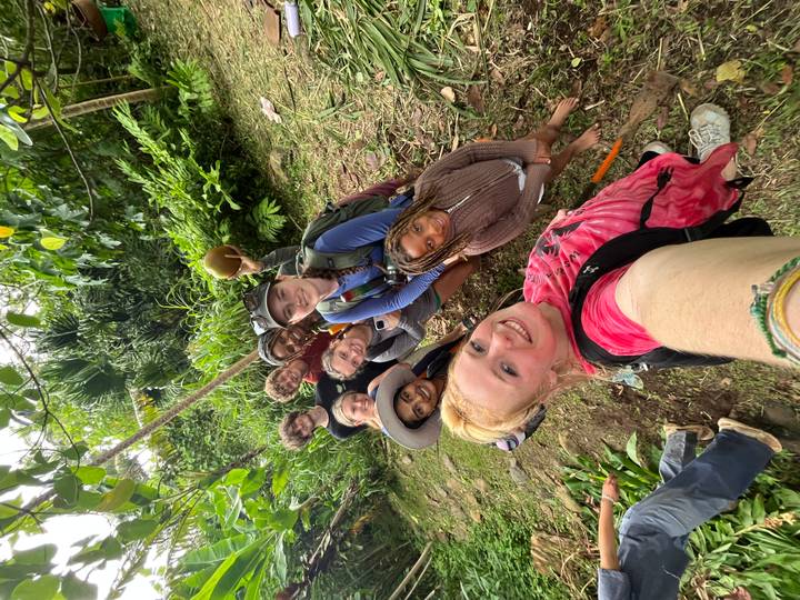 Energetic selfie of travellers in lush jungle holding a fresh coconut.