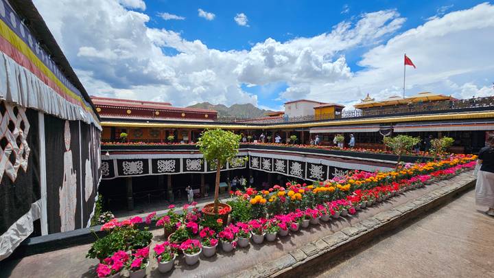 Inner courtyard of a Tibetan temple lined with pots of vibrant flowers.