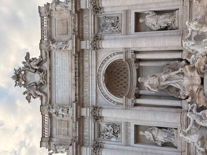 The ornate Trevi Fountain in Rome is captured in soft evening light, rich in marble detail.