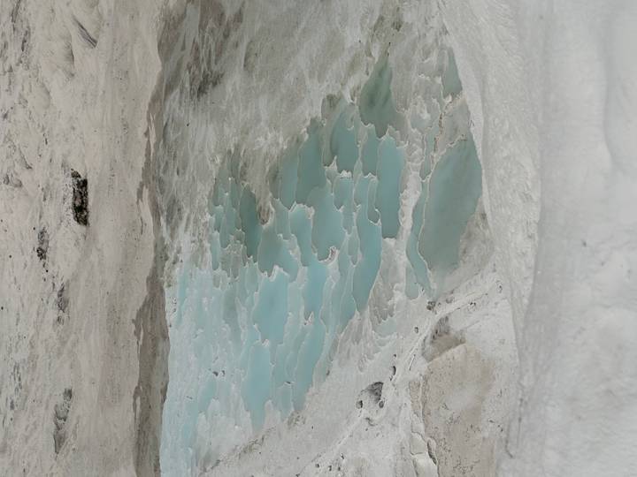 Terraced turquoise pools of Pamukkale filled with mineral water against white travertine landscape.