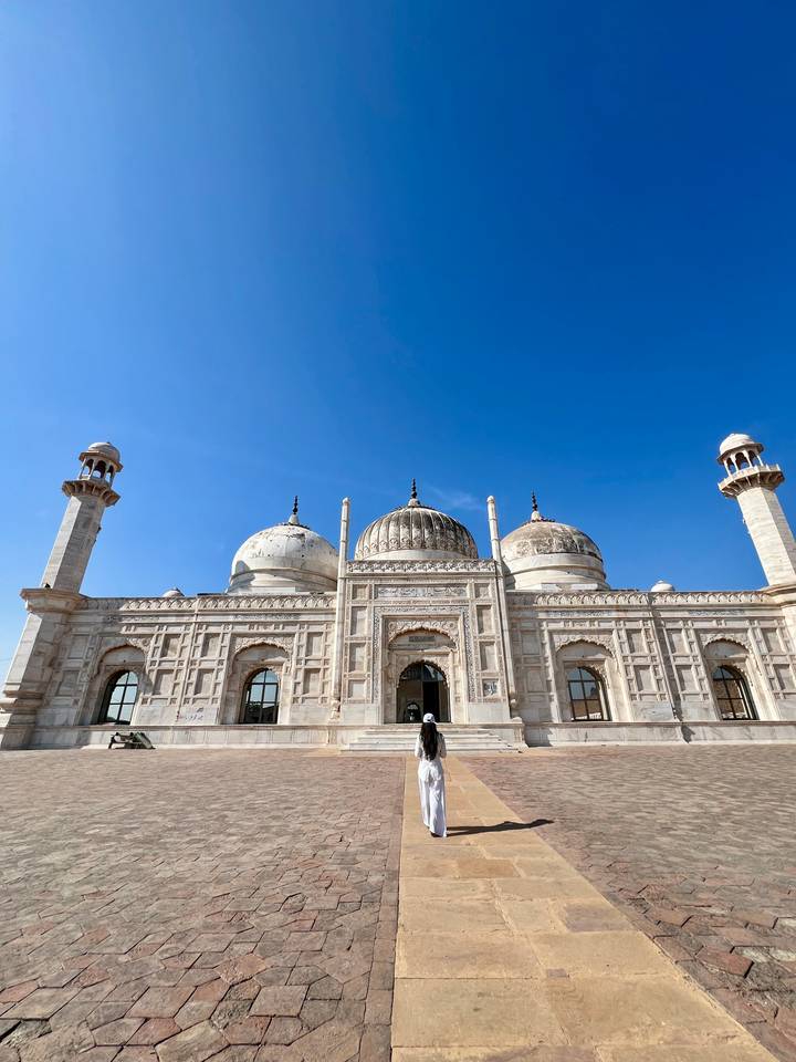 White marble mosque with three domes against deep blue sky in Pakistan.