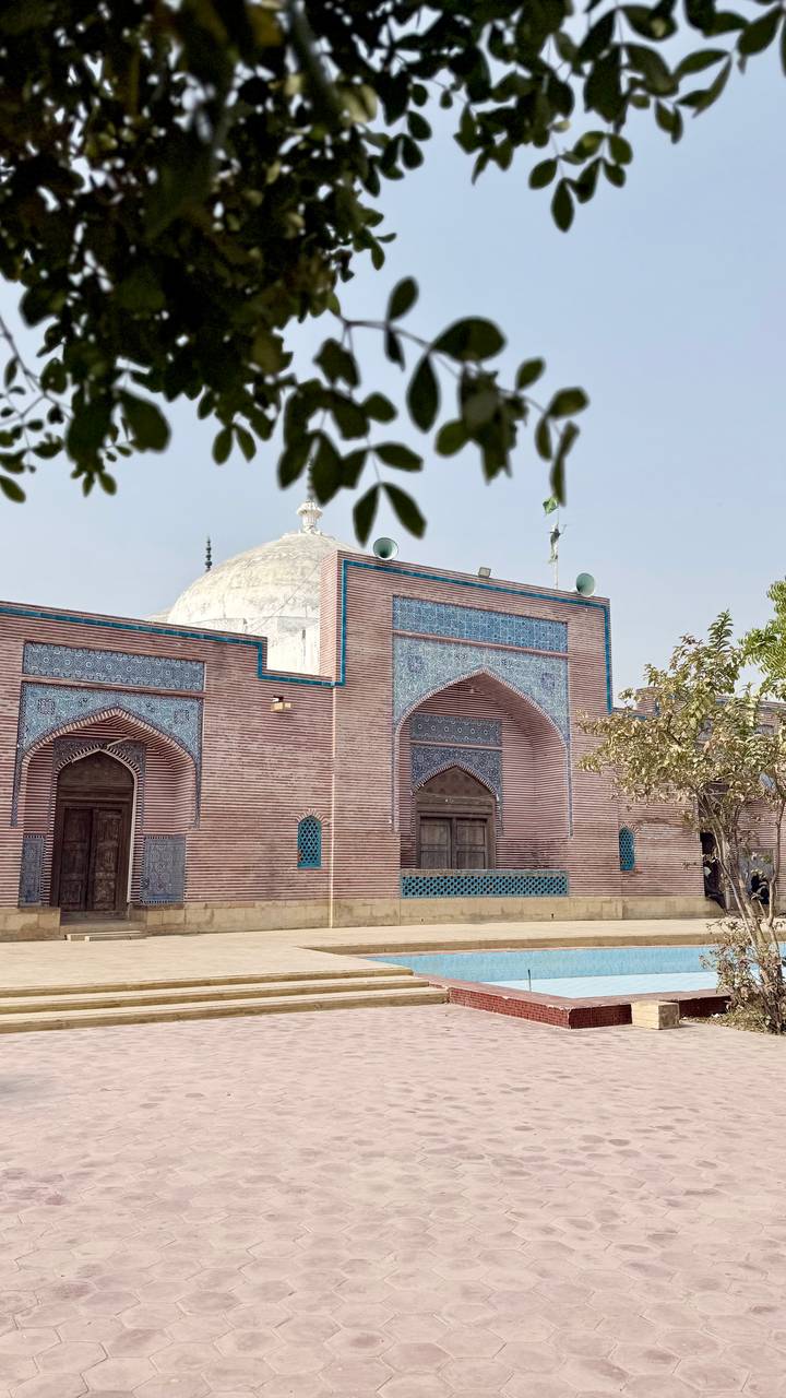 Side wall of Pakistani shrine with striped brickwork and decorative turquoise tiles.
