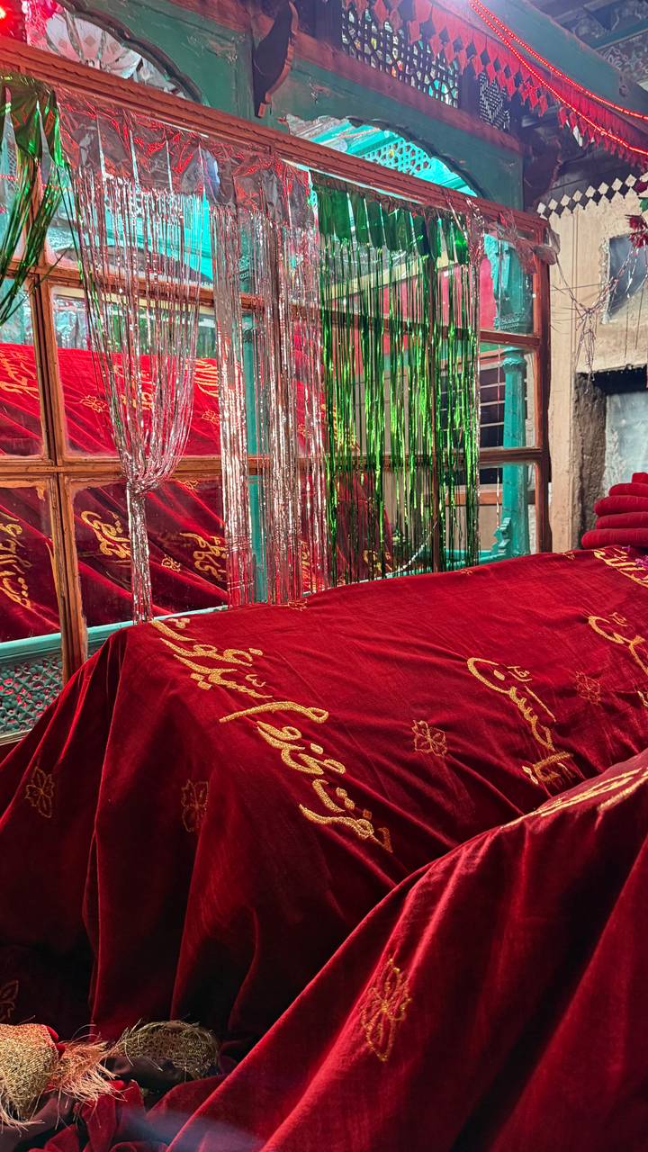 Interior shrine covered in red velvet cloth with metallic tinsel and calligraphy.