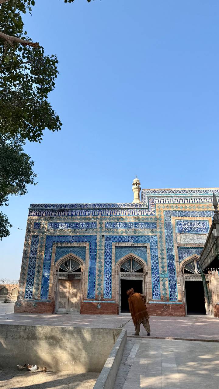 Blue-tile patterned wall and minaret tip of historic Pakistani mosque against sky.