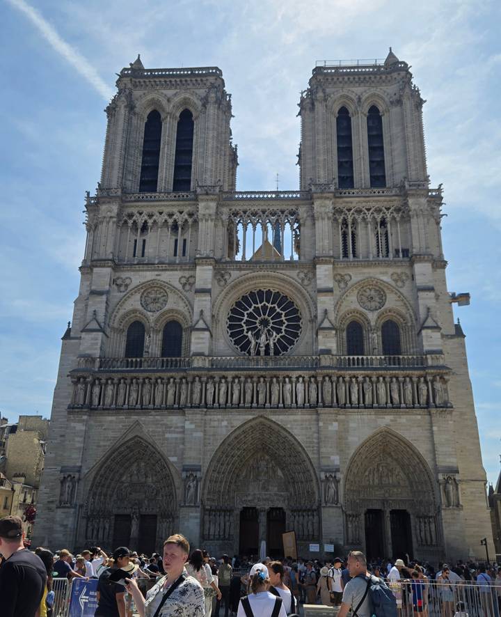 Front façade of Notre-Dame Cathedral in Paris showcasing its twin towers, large rose window and gothic stonework.