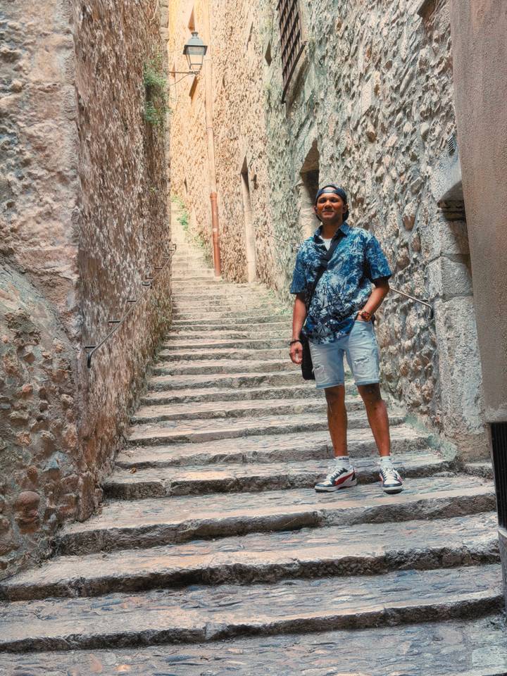 Traveller standing on narrow stone steps between rustic medieval walls in a historic European town.