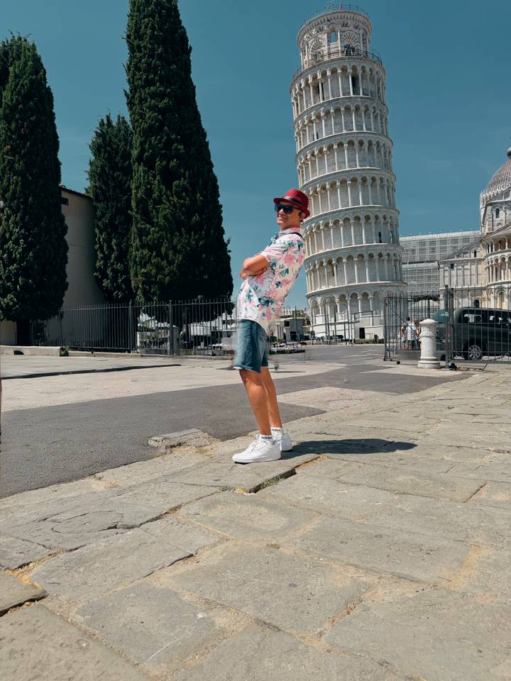 Comical leaning pose by the Leaning Tower of Pisa on a sunny afternoon.