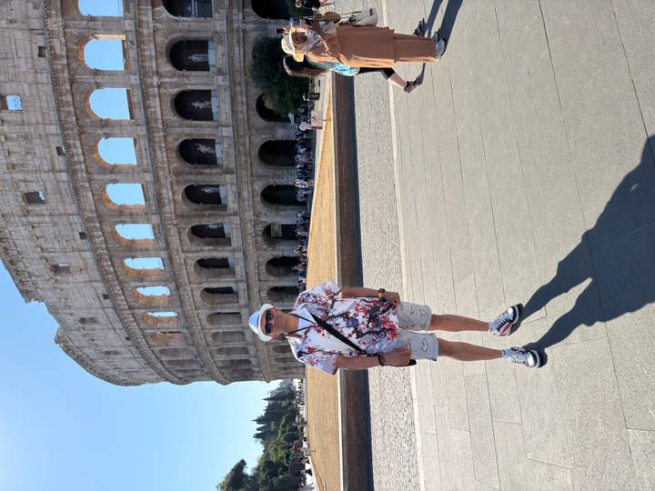 Traveller posing in front of the iconic Colosseum in Rome on a bright sunny day.