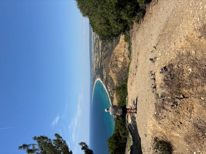 Single visitor admires a sweeping coastal panorama from a high clifftop viewpoint.