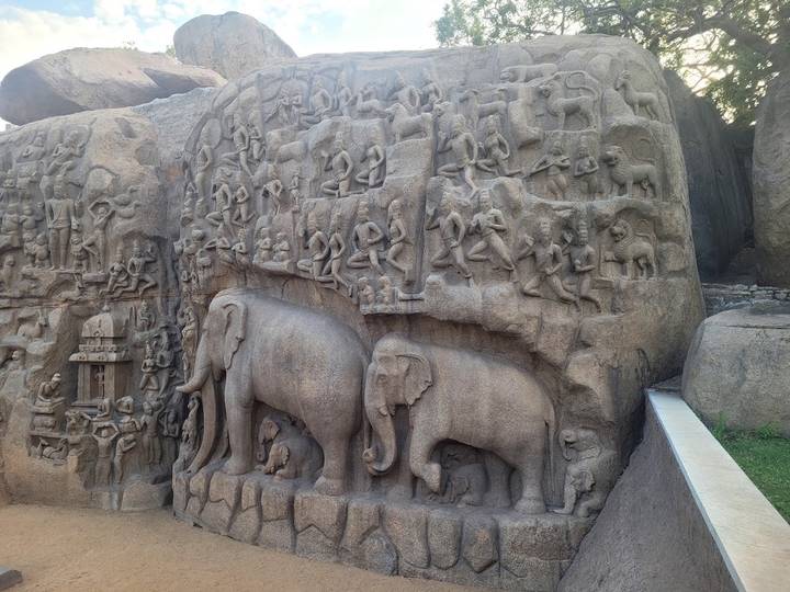 Massive rock relief depicting elephants and mythological figures, known as the Descent of the Ganges, carved into granite cliffs.