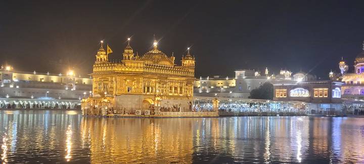 Golden Temple illuminated at night reflecting in the serene water tank.