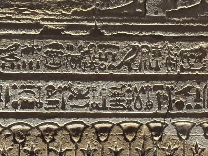 Detailed close-up of ancient Egyptian hieroglyphic inscriptions carved into stone.