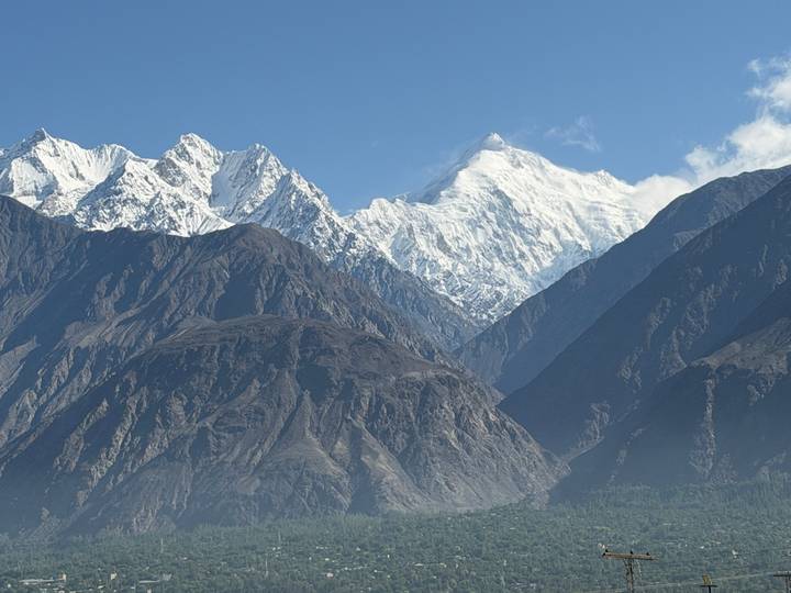 Snow-capped mountain peaks towering above dark rocky ridges under clear blue sky