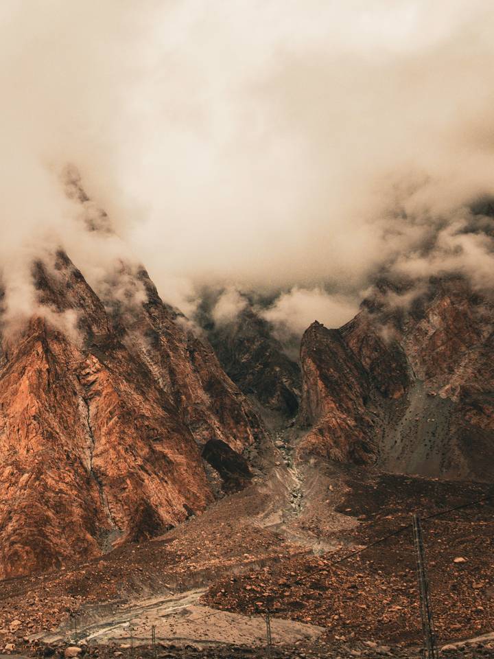 Rust-hued rocky peaks disappearing into low misty clouds.