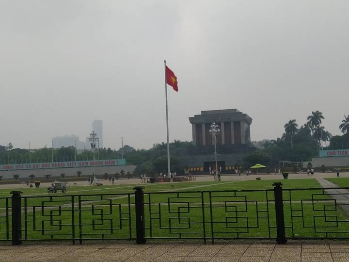 Ho Chi Minh Mausoleum and flagpole on an overcast day in Hanoi’s Ba Dinh Square.