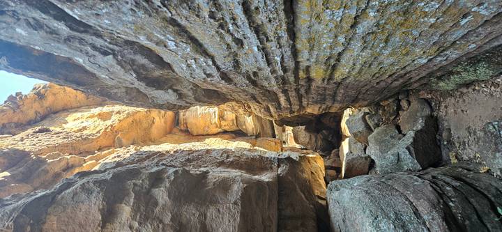 Narrow sandstone passageway with layered rock walls and scattered boulders