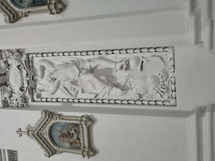 Elaborate white bas-relief sculpture inside ornate church interior.