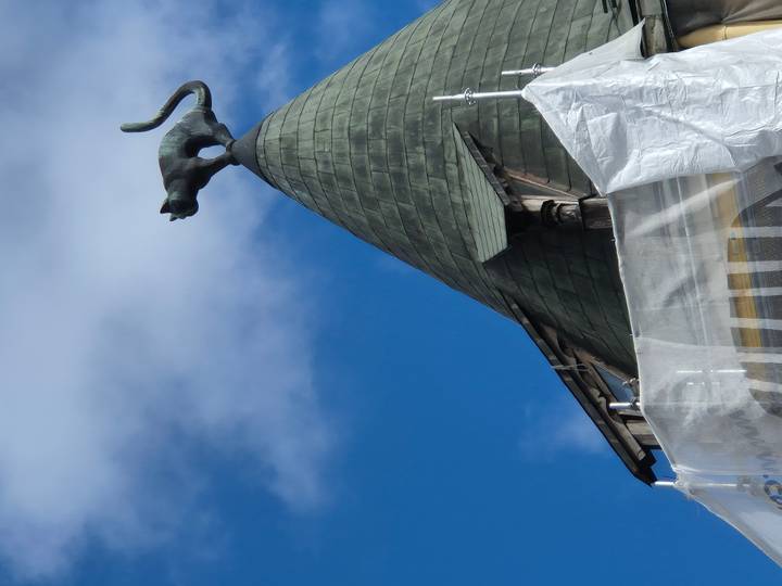 Famous cat statue perched on green rooftop against blue sky in Riga.