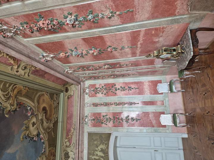 Elegant rococo room with painted ceiling, ornate walls and antique furniture.