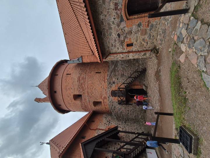 Visitors enter red-brick tower of Trakai Island Castle on cloudy day.