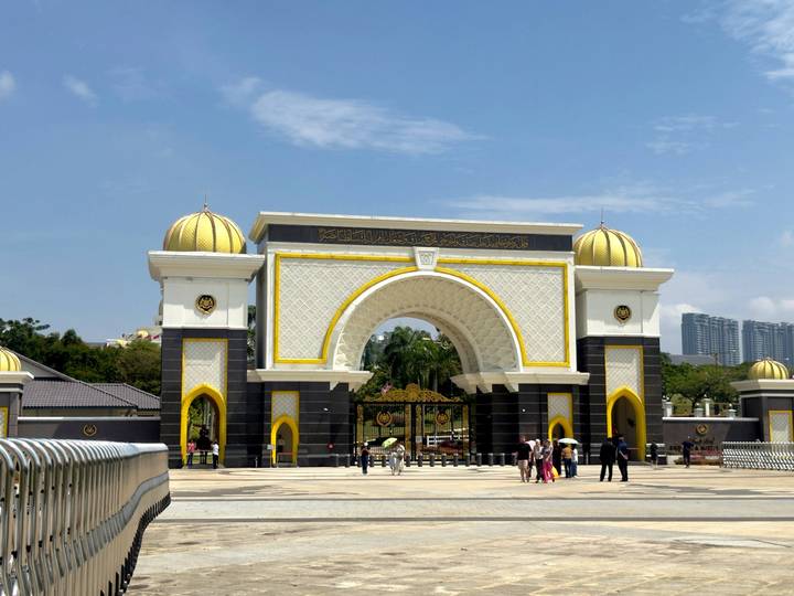 Grand white-and-gold main gate of Malaysia's Istana Negara with visitors taking photos