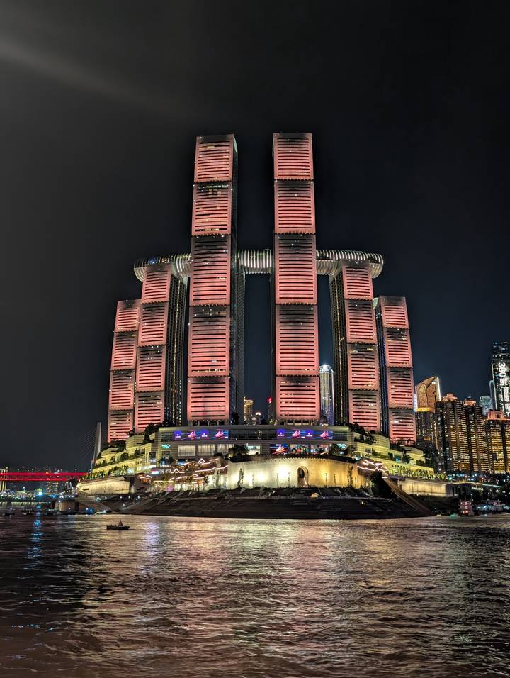 Night view of Chongqing’s futuristic Raffles City skyscrapers bathed in pink lighting against the dark sky.