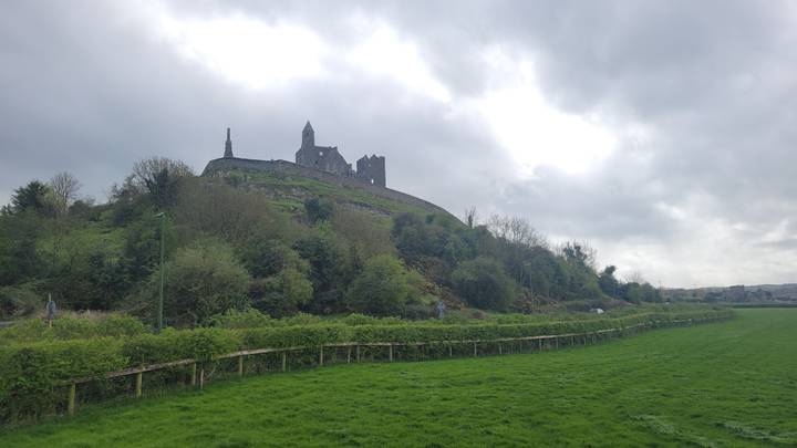 Rock of Cashel rising on a green hill beneath a cloudy grey sky.