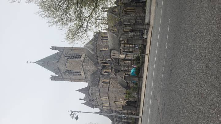Street-level view of Christ Church Cathedral with misty grey sky across an empty road.